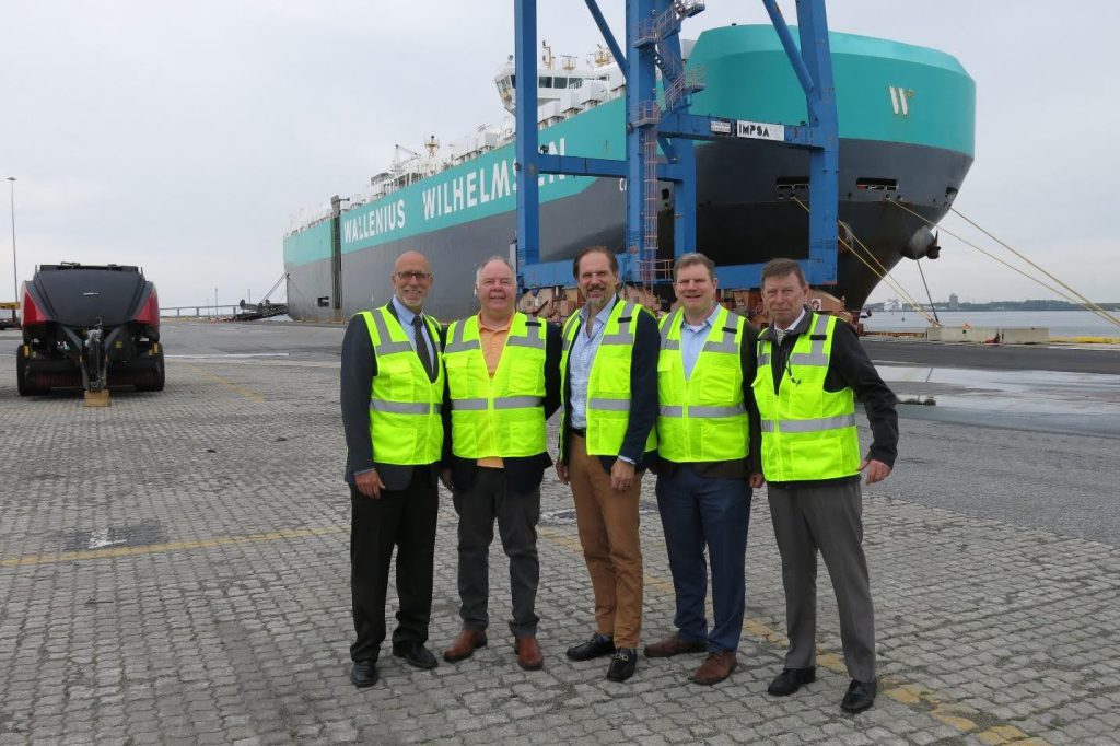 A group of men in yellow vests standing in front of a large ship