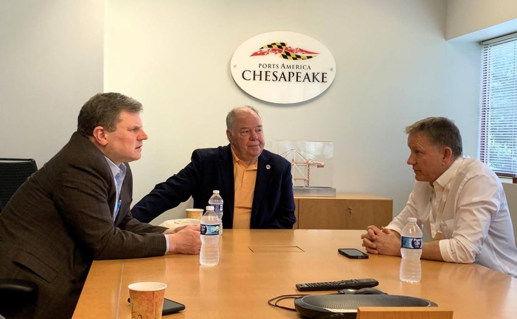 3 men at a conference table with the Ports America Chesapeake Logo in the background