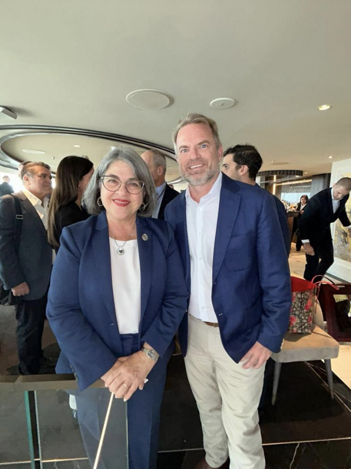 A woman and man in business attire posing after an event